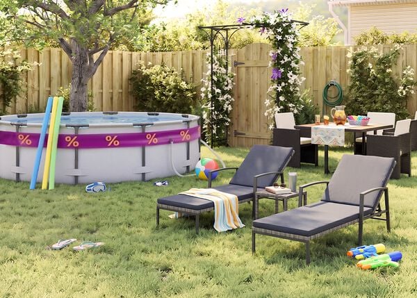 Zonnige achtertuin met opzetzwembad, zwembadnoodles, zwembril, strandbal en slippers in het gras. Twee zwarte metalen ligstoelen met grijze kussens staan naast een klein bijzettafeltje, terwijl een tuinset met donkere gevlochten stoelen is geplaatst bij een bloeiende pergola, houten schutting en groene tuinplanten.