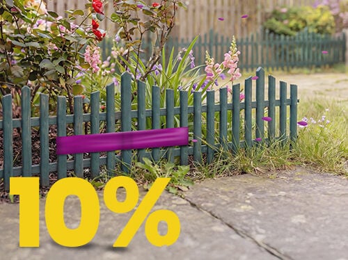 Bloembed in een tuin achter een groene houten omheining met een opvallende &ldquo;10%&rdquo; kortingsactie.