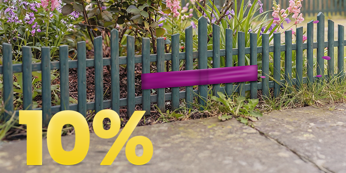 Bloembed in een tuin achter een groene houten omheining met een opvallende “10%” kortingsactie.