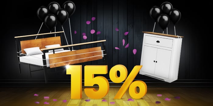 Houten en metalen bedframe en wit dressoir met zwarte ballonnen voor een felgeel 15%-teken op een donkere houten vloer.