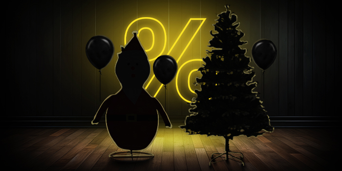 Opblaasbare kerstmanfiguur en kerstboom met zwarte ballonnen voor een felgeel procentteken op een donkere houten vloer.
