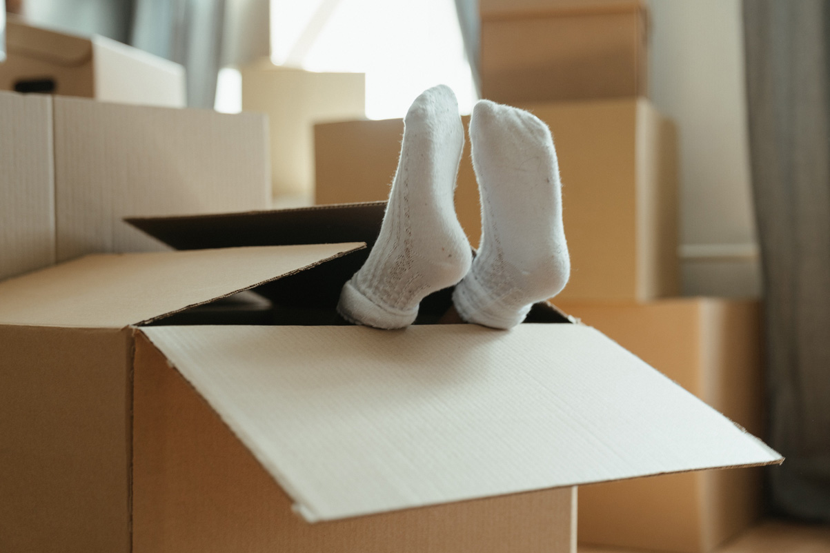 Kid's feet in a carton box during moving day